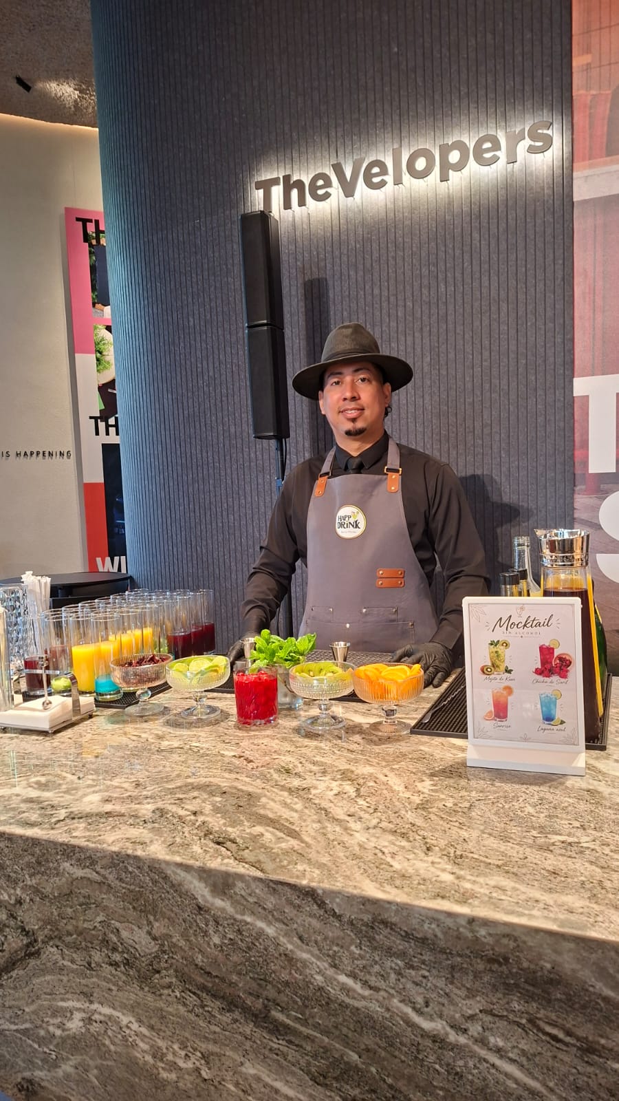 Bartender de Happy Drink en una barra de mocktails con bebidas y frutas para un evento