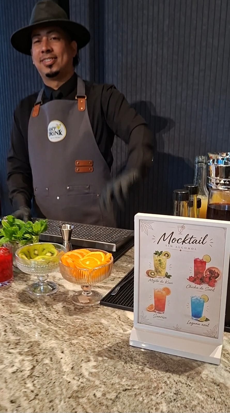 Bartender de Happy Drink junto a la carta de mocktails y frutas para las bebidas